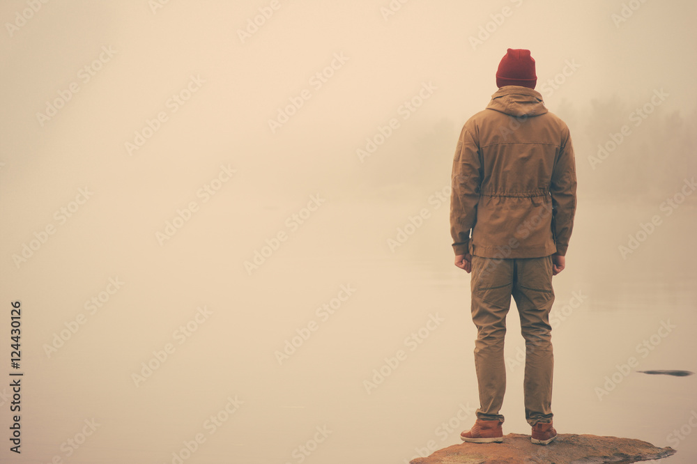 Fotografie Young Man standing alone outdoor with foggy scandinavian nature on background Tr