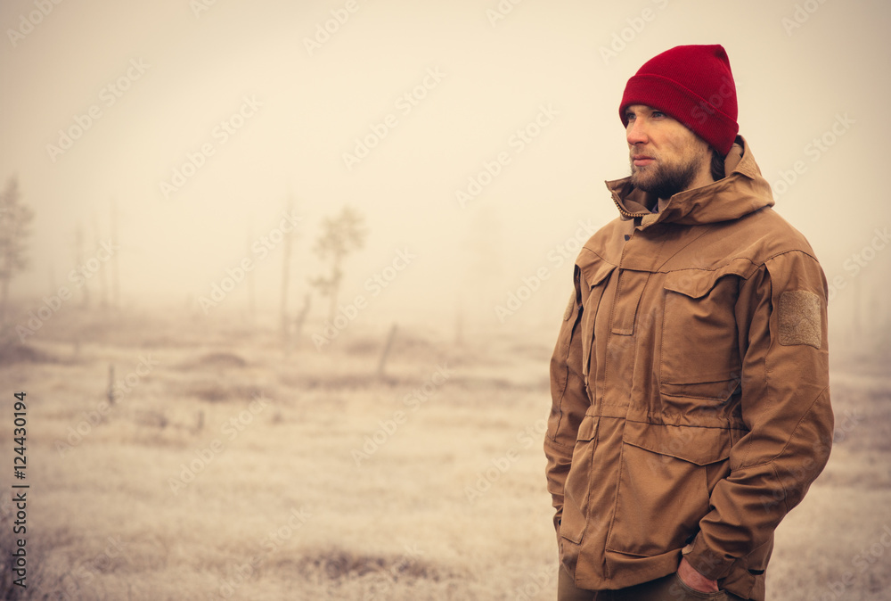 Young Man wearing winter hat clothing outdoor with foggy nature on background Travel Lifestyle and melancholy emotions concept film effects colors