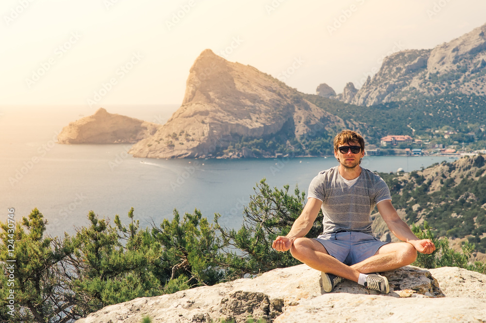 Young Man relaxing yoga on rocky mountains with sea on background Summer vacations and Lifestyle concept