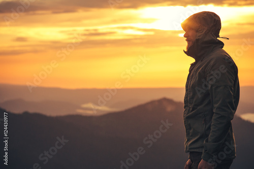 Young Man standing alone outdoor with sunset mountains on background Travel Lifestyle and survival concept