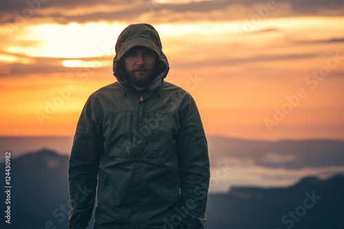 Man Traveler bearded standing alone outdoor with sunset mountains on background Travel Lifestyle and survival concept
