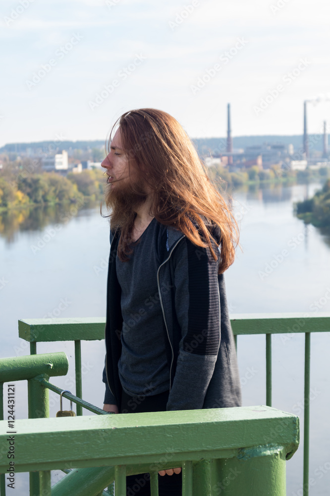 Portrait of man with a long beard and a long hair near the river