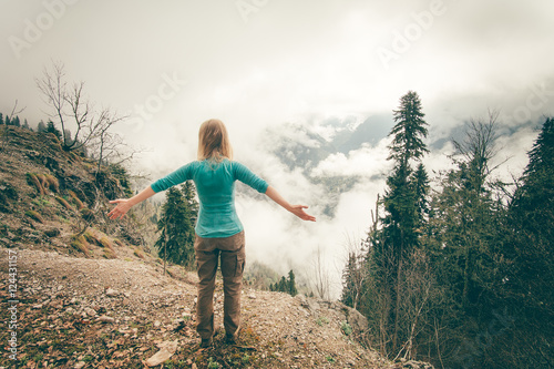 Young Woman raised hands relaxing outdoor with foggy forest on background Lifestyle Travel concept Summer vacations rear view