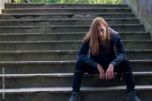 Portrait of man with a long beard and a long hair on the stairca
