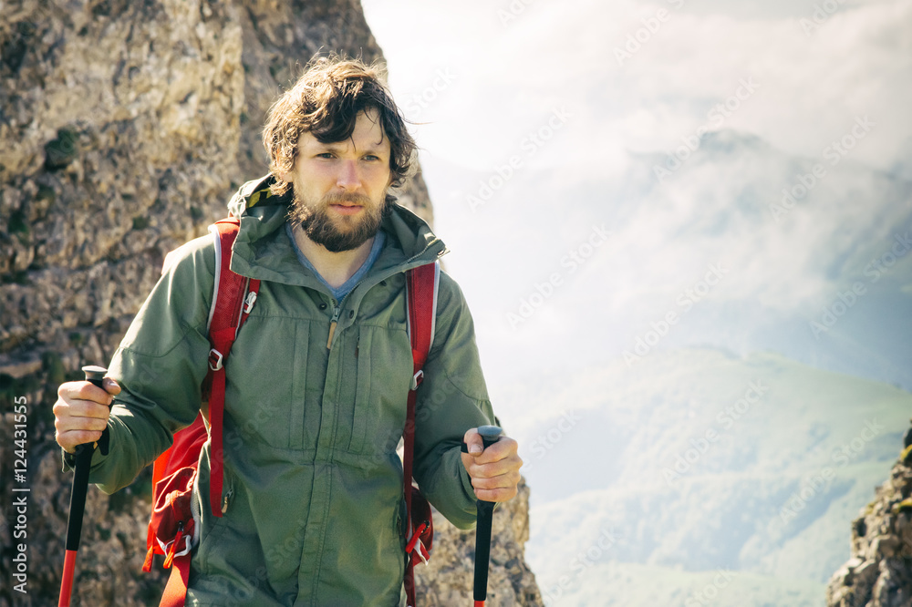 Young Man bearded with backpack and trekking poles relaxing outdoor Travel Lifestyle hiking concept rocky mountains on background Summer vacations