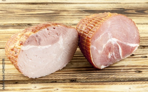 Smoked boneless pork ham hock wrapped in netting on a wooden background