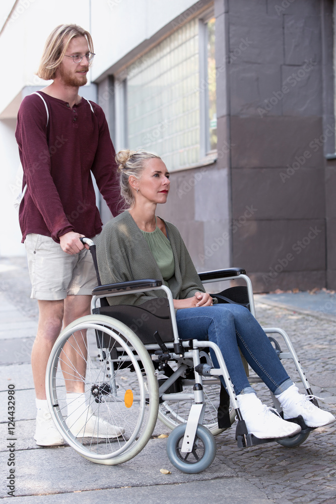 woman in wheelchair and man helping her woman in wheelchair and man helping her