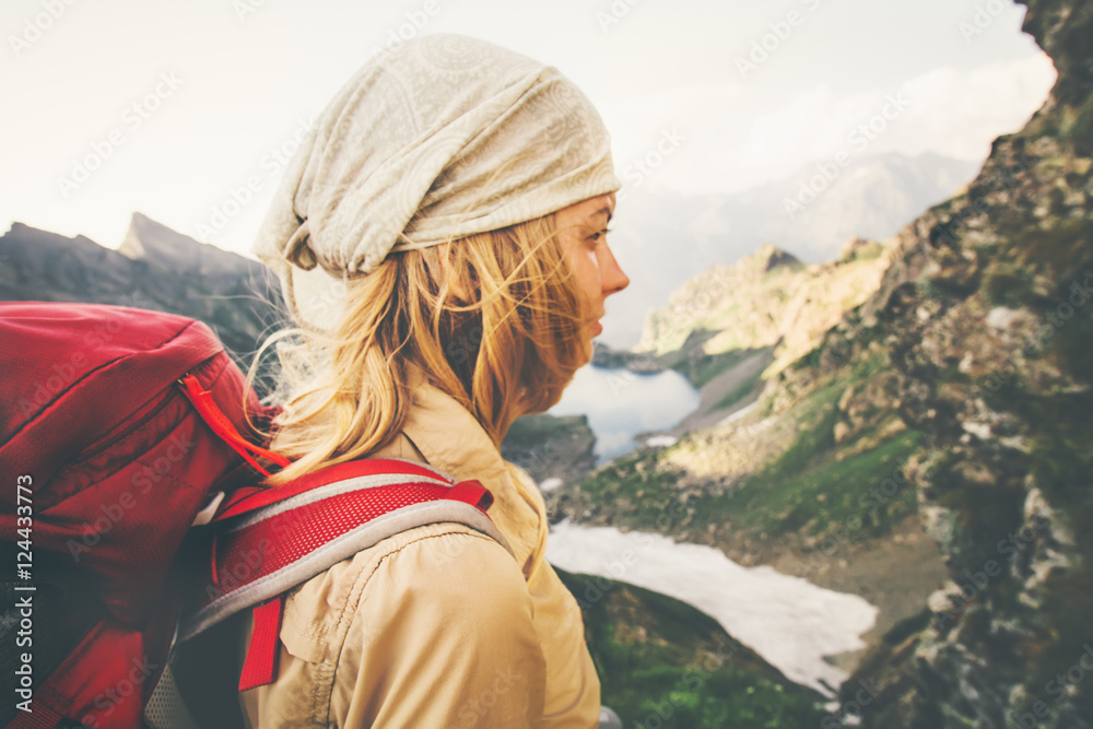 Young Woman with red backpack hiking alone Travel Lifestyle concept lake and mountains landscape on background Summer vacations outdoor. windy soft focus
