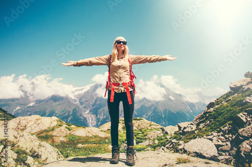 Woman raised hands with backpack relaxing with mountains and clouds landscape on background Travel Lifestyle concept active summer vacations