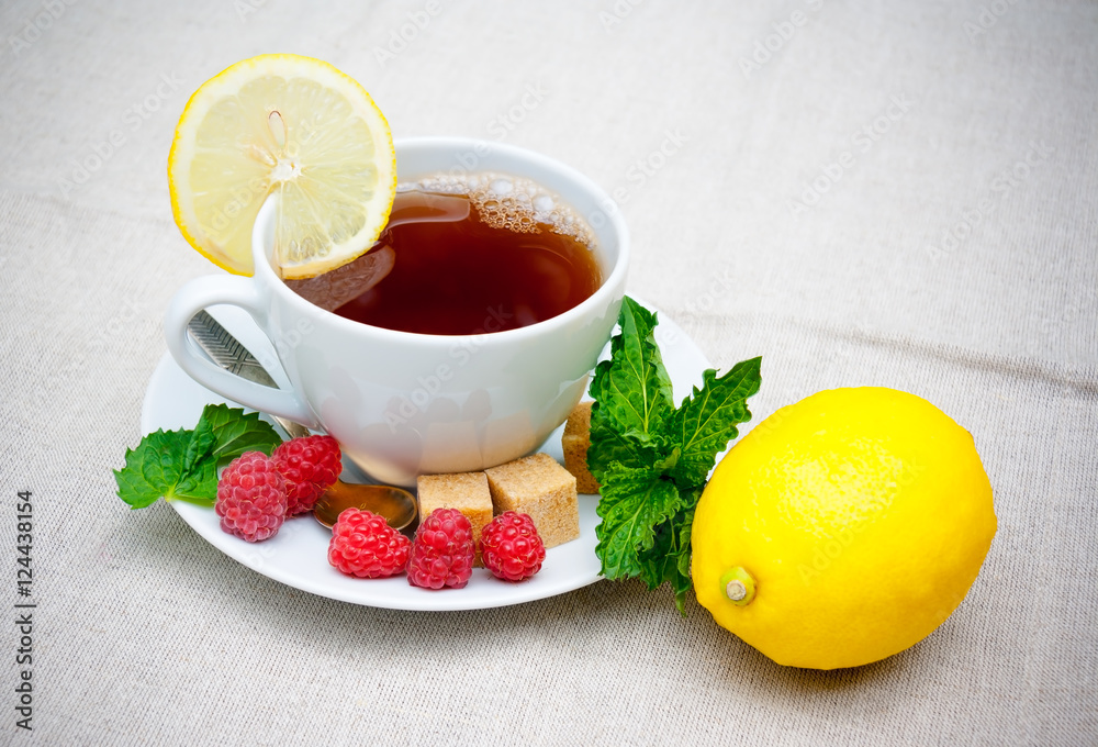 Tea with mint, brown sugar, raspberry and lemon on table Tea with mint, brown sugar, raspberry and lemon on table