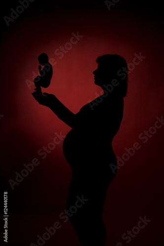 Pregnant woman holding in her hands the symbol of embryo