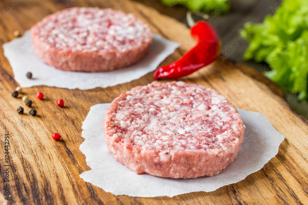 Raw fresh burger meat patties on wooden chopping board Raw fresh burger meat patties on wooden chopping board