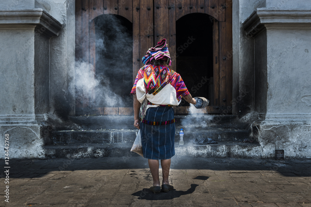 Naklejka premium Mayan woman performing a ritual in front of the Santo Tomás church in the town of Chichicastenango, in Guatemala