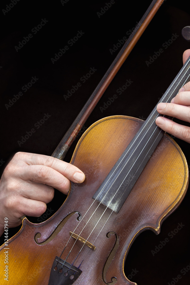 Men's hands with old violin in a black background Men's hands with old violin in a black background