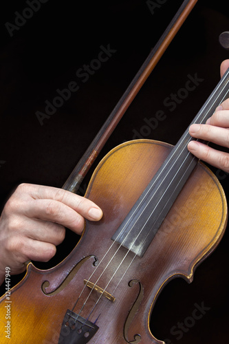 Men's hands with old violin in a black background