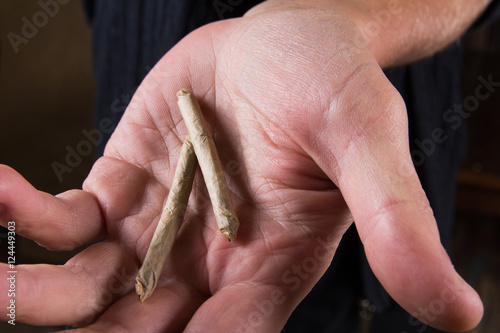 Marijuana joints in the mans hand. Man offering drugs