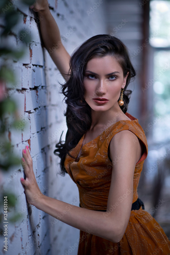 Obraz premium Pretty slim woman with yellow dress posing against stone wall