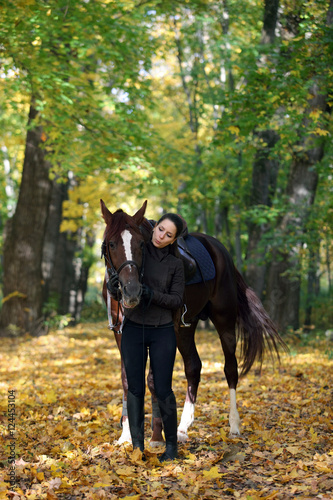 Young attractive girl with white arabian horse in the autumn forest 