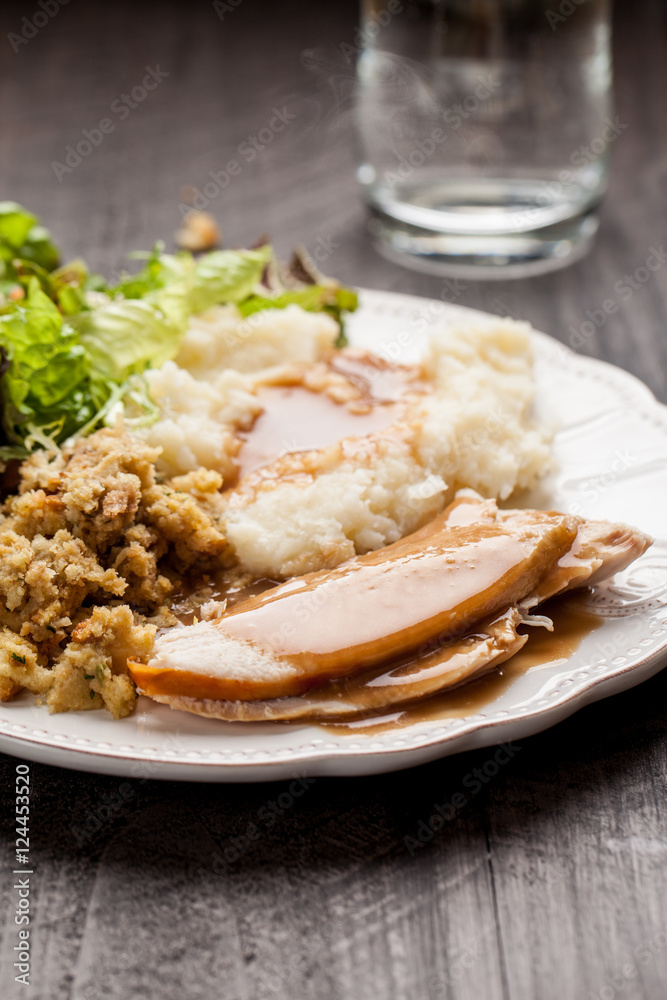 Oven roasted turkey Thanksgiving platter with mashed potatoes, gravy, salad, and stuffing with a cup of water