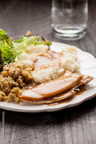 Oven roasted turkey Thanksgiving platter with mashed potatoes, gravy, salad, and stuffing with a cup of water