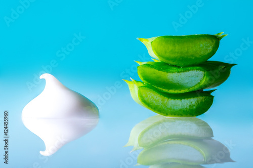 Cut aloe leaf texture macro with a drop of white cream with aloe extract on dark  blue background.
