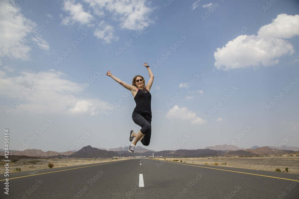 woman jumping at a emty road in rural Oman woman jumping at a emty road in rural Oman