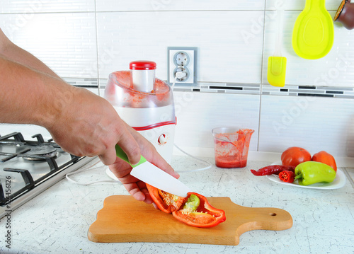 hand cut with a knife the red pepper on a cutting board. Juicing fresh vegetables. Fresh Juice photo