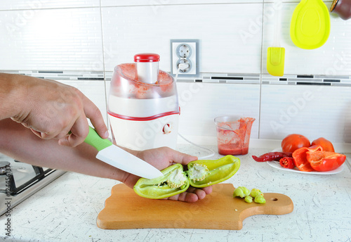 hand cut with a knife the green pepper on a cutting board. Juicing fresh vegetables. Fresh Juice photo