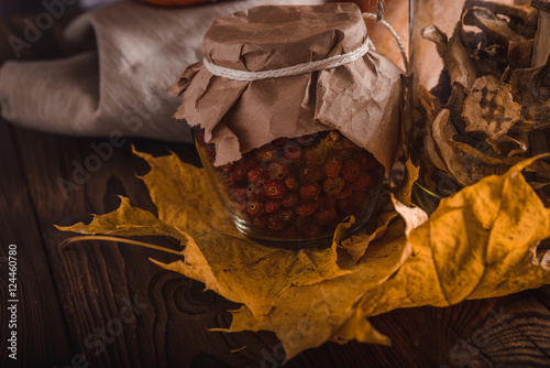Fotografi Rosehips in a glass jar on a wooden table in rustic style