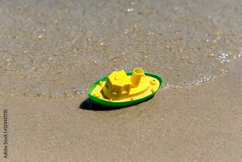 Toy boat in the wet sand of the sea. Summer holidays at sea. Boat trips.