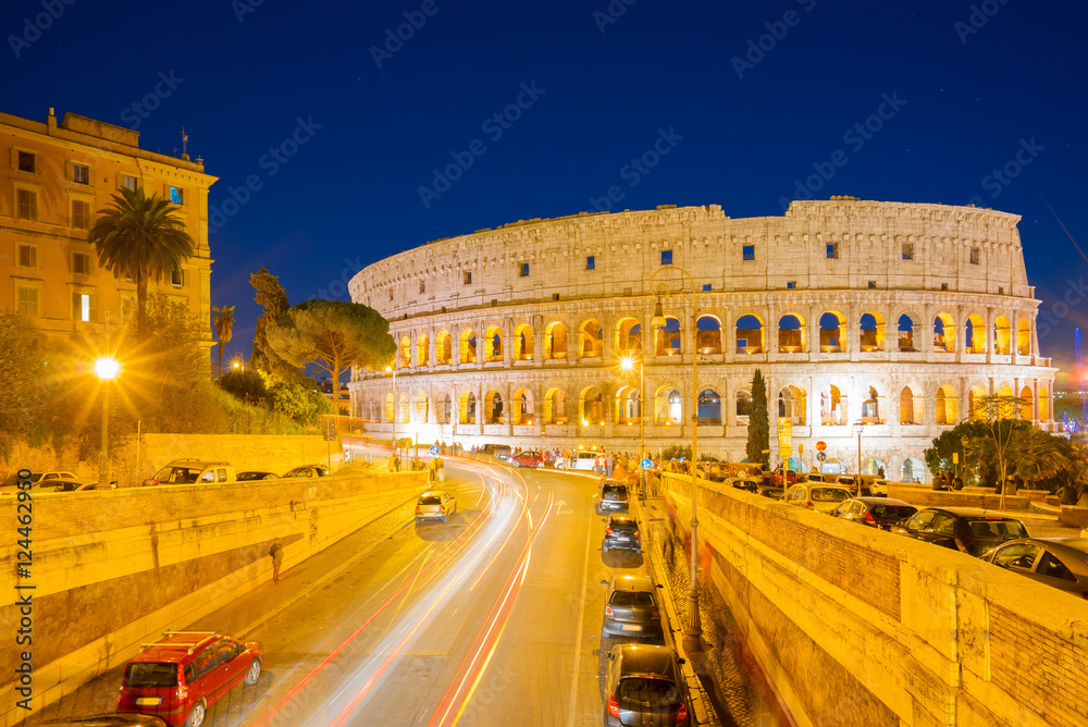 view of Colosseum illuminated at nighwith traffic lightst in Rome, Italy