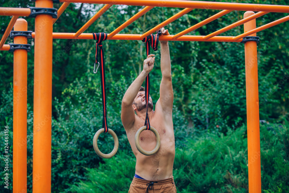 Fototapeta premium Muscular man exercising on outdoor gymnastic ring.