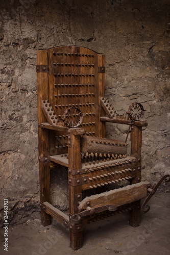 Medieval spiked torture armchair in dark room photo