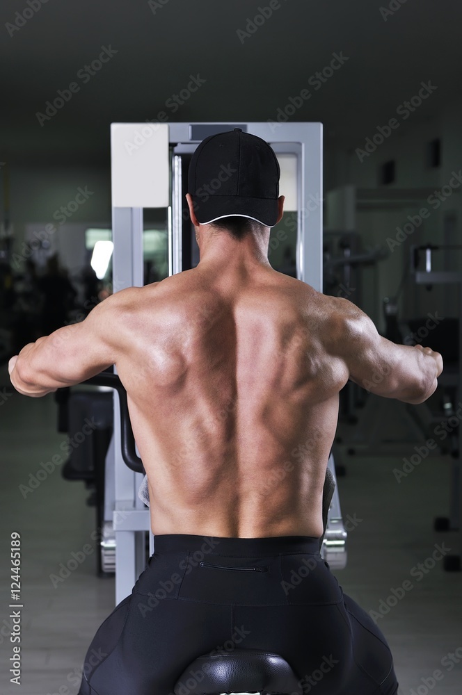 Handsome powerful athletic man performing back exercise. Strong bodybuilder with perfect muscles.