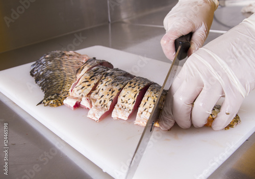Cook cut up raw fish in kitchen