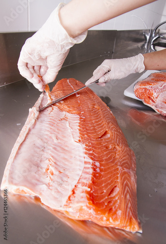 Cook cut up raw fish in kitchen