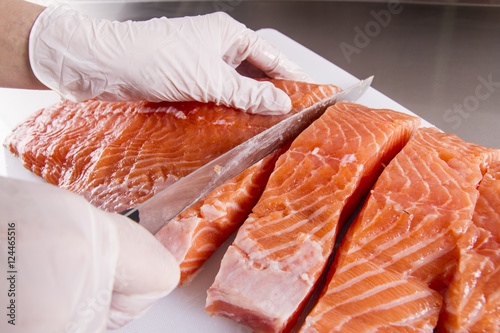Cook cut up raw fish in kitchen