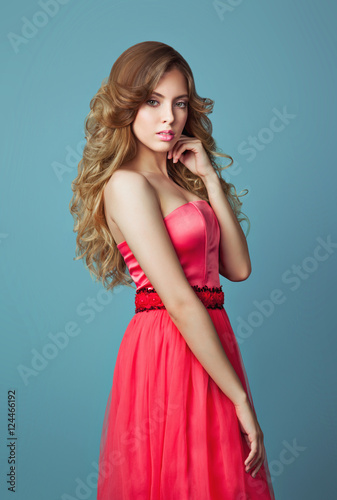 Beautiful girl in coral dress. Picture taken in the studio on a blue background