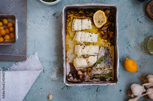 Baked white fillet fish in an aluminium baking tray. Top view photo