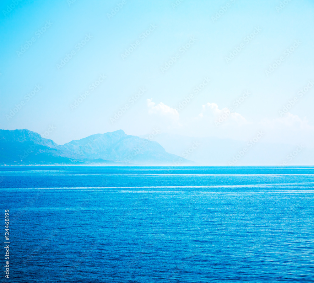 Calm Blue Sea with Mountains in Haze. Seascape.