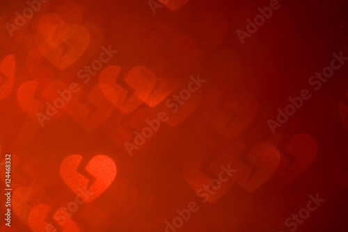 De-focused broken luminous hearts on red  left side . Abstract red background