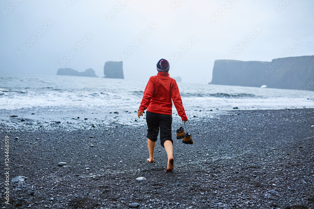 woman walking along the beach in a storm. black sand beaches on the Atlantic coast in Iceland