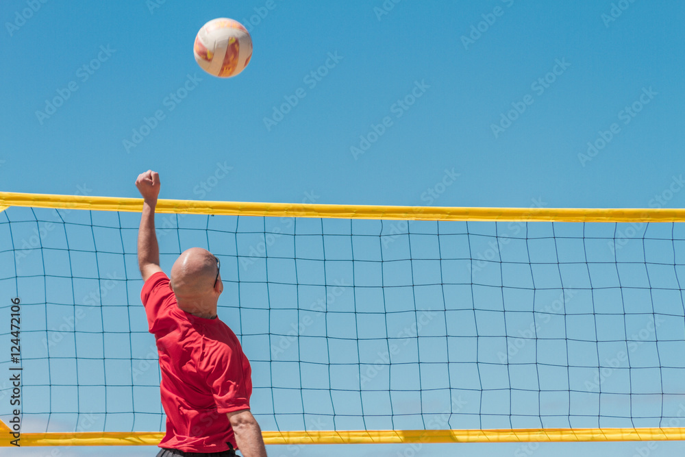 A beach volleyball player pass the ball with a blue sky backgrou