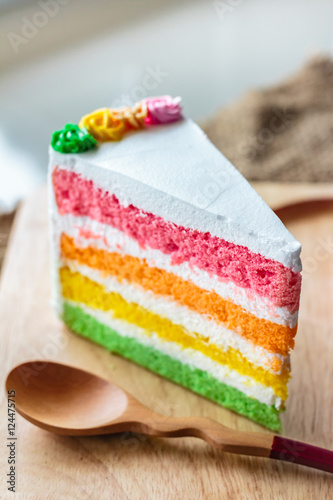 Delicious rainbow cake on wood plate.