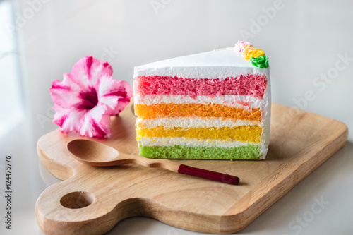 Delicious rainbow cake on wood plate.
