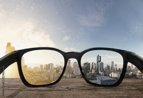 Sunglasses on wooden desk with tropical city view in sunrise view background