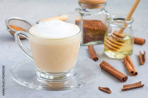 Healthy rooibos red tea latte in glass cup and ingredients on background, horizontal