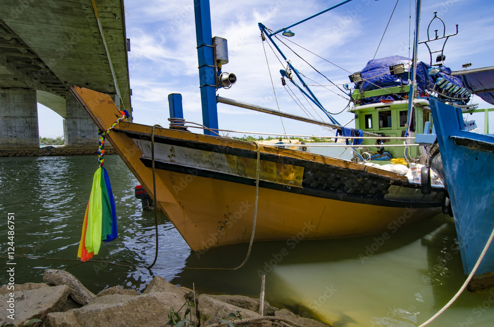 fisherman boat anchored over cloudy and blue sky background at s