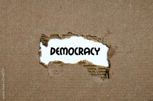 The word democracy appearing behind torn paper