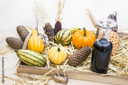 Autumn mood with decorative pumpkins, corns, pine cones, a bottle of red wine and straw